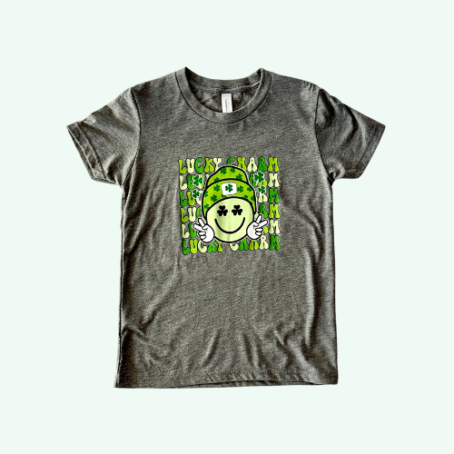 Charcoal gray t-shirt featuring a 'Lucky Charm' slogan with a green shamrock hat and a smiling face design on a white background