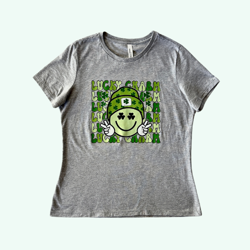 Gray short-sleeved t-shirt with 'Lucky Charm' text and smiling face with a green hat and shamrocks design